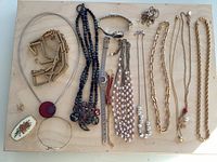 All twelve jewelry pieces and wristwatch arranged on board for full view