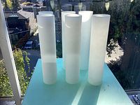 Five frosted glass cylindrical shades standing upright