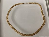 Full view of braided gold-tone necklace laid flat