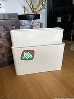 Front view of white Kartell magazine rack with 7-Up sticker