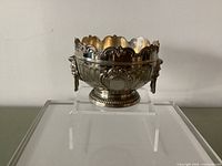 Front view of silver-plated Monteith bowl showing scalloped rim, cartouche, fluted body and lion head handle