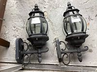 Pair of matching black outdoor wall lanterns showing overall design and condition