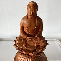 Front view of carved wooden Shakyamuni Buddha statue on lotus base