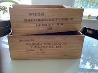 Two stacked wooden wine crates with stamped import and bottler information