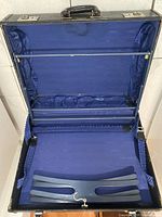 Suitcase open showing blue interior, hanger bar and straps