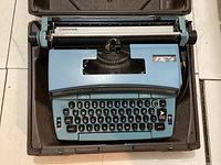 Top view of blue Smith-Corona Coronet Super 12 electric typewriter inside hard case