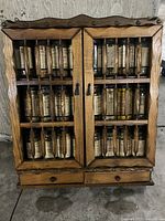 Front view of closed wood cabinet showing rows of spice jars behind glass doors