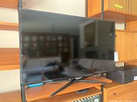 Front view of Samsung 40-inch TV on wooden stand, showing its screen and stand shape.