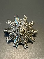 Top view of brooch showing starburst design and marcasite stones in silver setting.