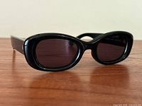 Front angled view of black oval Aire sunglasses showing glossy frame and dark lenses.