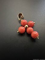 Front view of coral bead cross pendant on black background