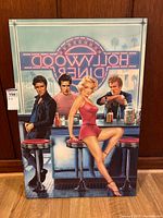 Full front view of the Hollywood Diner wall art with backlit neon style lights and four figures sitting at a diner counter.