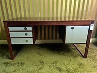 Front view of rosewood desk showing top surface, left and right drawer banks and sled base