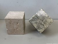 Travertine and marble cubes side by side showing size and surface texture including pits on travertine and chips