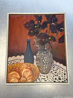 Front view of the oil painting showing the full composition including the flowers, bottle, croissants, and frame.