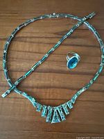 Full view of necklace, bracelet, and ring on wooden surface