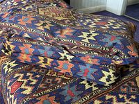 Close-up of the cotton comforters showing the colorful ethnic kilim pattern with geometric motifs in blue, red, yellow and orange.
