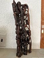 Front view of the rosewood carving showing the tall, vertical sculpture with multiple connected human figures.