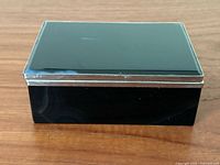 Top and front side view showing the polished black stone surface and metal trim.