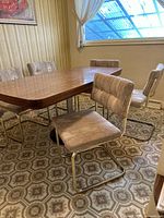 Set of six vintage cantilever dining chairs around wooden table showing upholstery and frame style from an angle