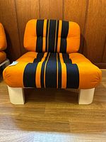 Front view showing orange and black striped seat and back cushions on white tubular frame