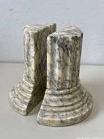 Pair of vintage marble column book ends shown from an angled view, displaying the fluted column design and rounded base.