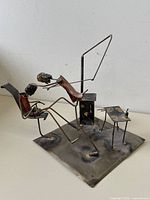 Full view of the brutalist metal sculpture showing both dentist and patient, dental chair, base, and small dental instrument table.