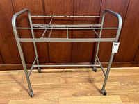 Front view of the vintage metal industrial cart showing the rectangular frame, caster wheels, and adjustable lever.