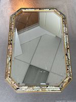 Photo showing full octagonal shape of mirror with visible floral patterned frame and beveled glass.