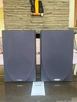 Front view of two Paradigm Atom v4 bookshelf speakers covered with black cloth grille, showing Paradigm logo on each.