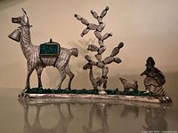 Full frontal view of the entire silver sculpture showing the llama, dog, shepherd and cactus on the rectangular base.
