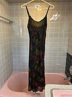 Full view of the dress hanging on a white plastic hanger showing front side and length ending around mid calf, showing vibrant multicolor velvet pattern.