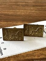 Front view of vintage 800 silver cufflinks with raised horse-drawn chariot design.
