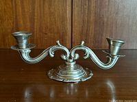 Front angled view showing the full double-armed sterling silver candlestick holder with elegant scroll design and weighted base.