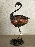 Full frontal view of the heron figurine showing the bird's head, neck, detailed wings in silver, and its granite stone body.