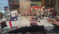 Photo showing Christmas decorations and linens arranged on a table including snowman figurine, framed signs, candles, and various ornaments