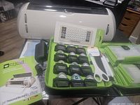 Cricut Expression electronic cutter shown alongside 12 cartridges in green case, cartridge overlay keyboard, scissors, user manual, and power adapter.