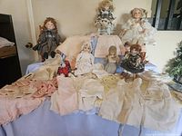 Full view of collection on display including dolls, doll clothes, wooden chairs, and blankets