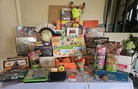 Wide view of all items on table including board games, dolls, globes, and gaming accessories