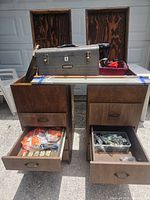 Front view of two wooden tool storage units on wheels with drawers opened showing hardware and tools inside, metal toolbox and red organizer tray on top