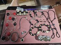 Full overview of assorted jewelry lot including multiple necklaces, bracelets, earrings, and a foot chain, arranged on a table.
