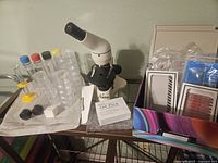 Full view of microscope with lab supplies including petri dishes, specimen vials, tab pack and slide covers