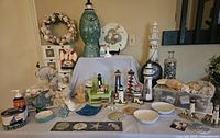 Full view of nautical themed decor on table including lighthouses, storage containers, candles, seashell and starfish items, and bathroom set