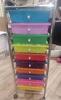 Front view showing colorful drawers stacked in metal frame with chrome tubular construction, each drawer with silver knob handle
