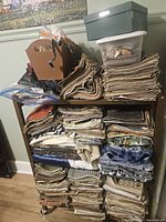 Shelf stacked with multiple folded fabric pieces of different colors and patterns along with boxes of sewing notions on top