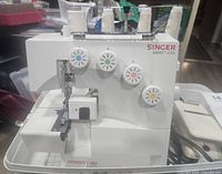 Front and side view of Singer Merritt Lock 3-4 thread overlock machine showing four colored tension dials and threading paths.