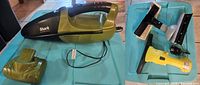 Photo showing Shark cordless handheld vacuum in olive green with charging cord and detachable nozzle.