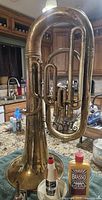 Full profile view of vintage brass baritone horn with some bottles including brass cleaner in front.
