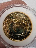 Front view of the gold plated Georgia peach quarter coin in clear capsule showing state name, figure and inscriptions.