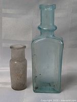 Both bottles shown side by side on a white fabric background, highlighting size and color difference